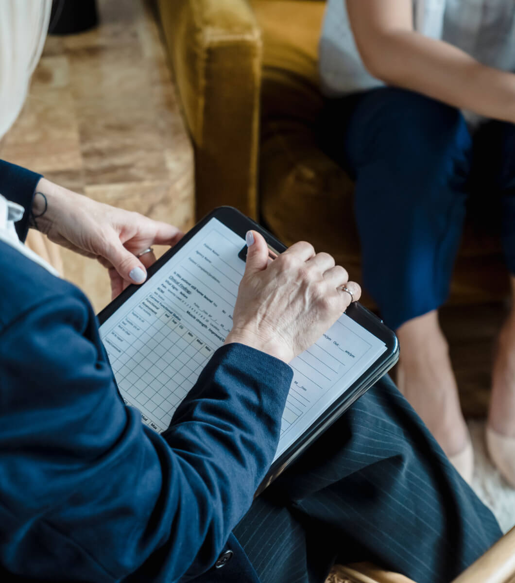 Person taking notes while reviewing documents during a consultation